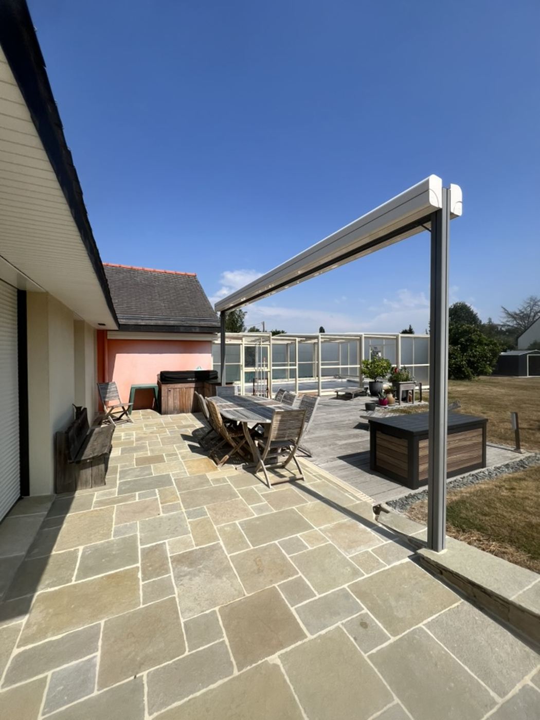 Aménagement extérieur par Nouvel Espace — terrasse en pierre avec pergola bioclimatique